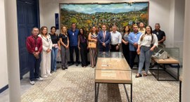 #PraTodosVerem: Na fotografia, aparece um grupo de pessoas em pé em frente a um espaço expositiv...