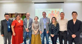 #PraTodosVerem: Na fotografia aparece um grupo de pessoas posando para foto tendo ao fundo a exi...