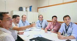 #PraTodosVerem: Na fotografia aparece uma sala de reunião com uma mesa branca retangular. Seis h...