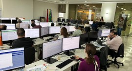 Capa#PraTodosVerem: na fotografia aparece várias pessoas sentadas em frente a computadores. Em p...