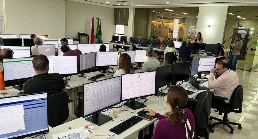 Capa#PraTodosVerem: na fotografia aparece várias pessoas sentadas em frente a computadores. Em p...