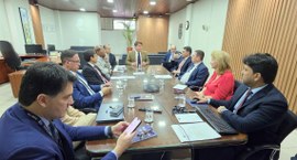 #PraTodosVerem: Na fotografia aparece uma sala de reunião, tendo várias pessoas sentadas em torn...