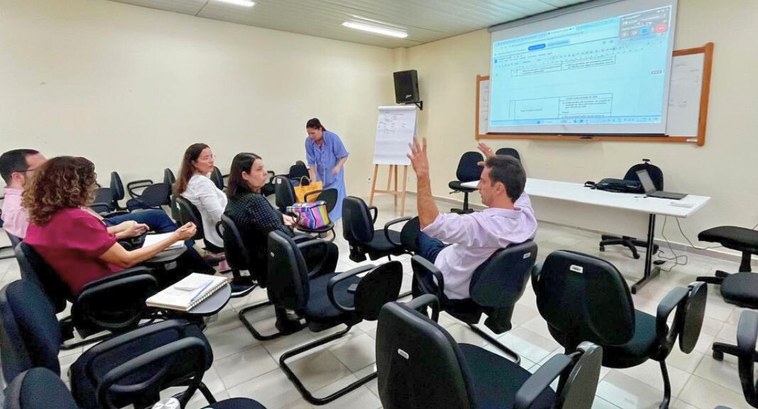 #PraTodosVerem: Na fotografia aparecem várias pessoas numa sala de reunião interagindo, tendo ao...