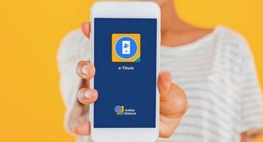 #PraTodosVerem: Foto de uma pessoa segurando um celular com a tela inicial do aplicativo e-Títul...
