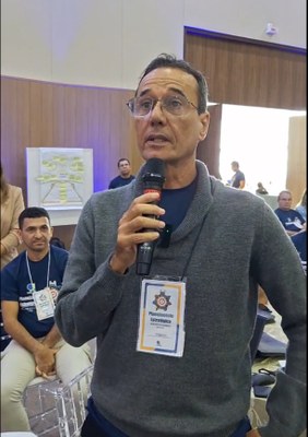 #PraTodosVerem: Na fotografia aparece, em primeiro plano, um homem falando em um microfone.