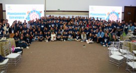#PraTodosVerem: Na fotografia aparecem muitas pessoas, algumas em pé e outras sentadas no chão, ...