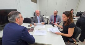 #PraTodosVerem: Na fotografia aparecem quatro pessoas reunidas em torno de uma mesa analisando p...