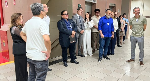 Foto 1: #PraTodosVerem: Na fotografia aparece um grupo de pessoas em um corredor de prédio públi...