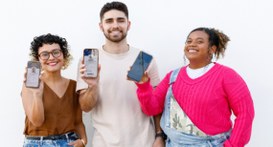 #PraTodosVerem: Na fotografia aparecem duas mulheres e um homem segurando um smartphone.