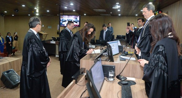 #PraTodosVerem: Na fotografia aparece uma mulher de toga preta assinando um documento sobre uma ...