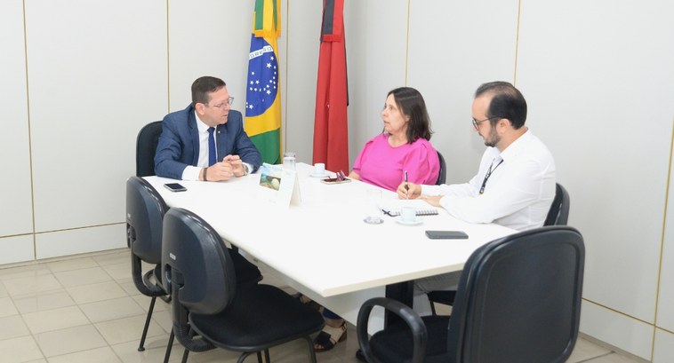 Justiça Eleitoral avança nos preparativos para lançamento do Projeto Cuidar #PraTodosVerem: Na fotografia, aparecem dois homens e uma mulher, sentados à mesa, sugerindo uma...