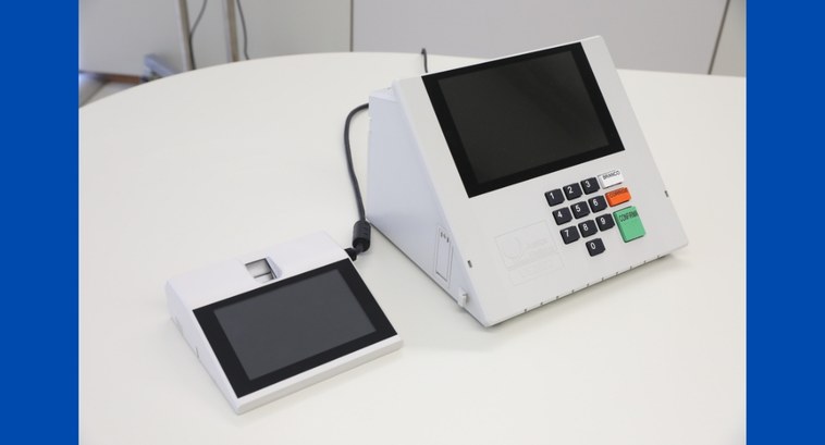 #PraTodosVerem: Na fotografia aparece uma urna eletrônica de votação sobre uma mesa.