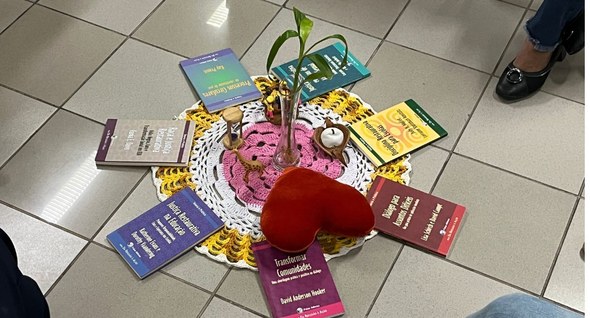 #PraTodosVerem: Na fotografia interna aparece um tecido colorido no chão em formato circular, co...