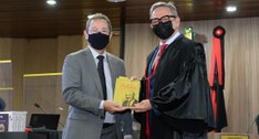 #PraCegoVer: Desembargador Leandros dos Santos entrega livro ao juiz José Ferreira Ramos Júnior.