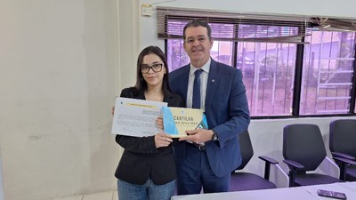 #PraTodosVerem: Na fotografia aparecem uma mulher e um homem, em pé, posando; ambos seguram um d...
