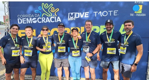 Mais de 700 pessoas participam da 2ª Corrida da Democracia em Campina Grande #PraTodosVerem: Na fotografia interna 3 aparece um grupo de pessoas do TRE-PB posando no backdro...