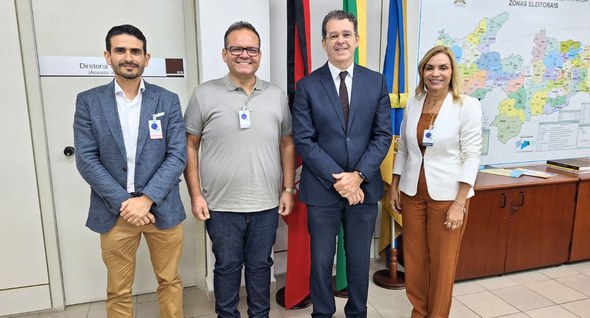 #PraTodosVerem: Na fotografia aparecem quatro pessoas em pé posando para fotos na sala da presid...