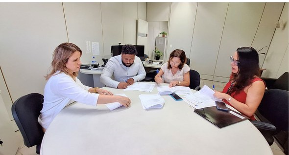 #PraTodosVerem: Na fotografia aparecem quatro pessoas sentadas à mesa, duas delas assinando um d...