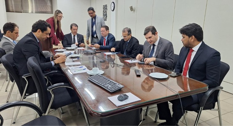 #PraTodosVerem: Várias pessoas sentadas em cadeiras ao redor de uma mesa de reunião.