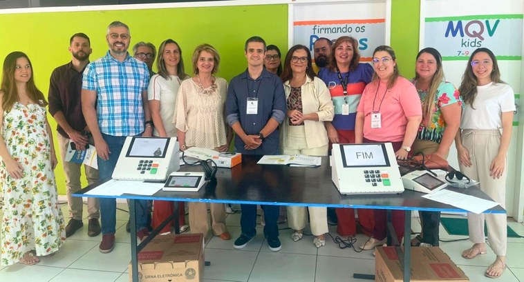 Mesárias e mesários são capacitados pela 76ª Zona Eleitoral #PraTodosVerem: Na fotografia aparecem em pé, posando, várias mulheres e homens; em primeiro pla...