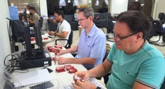 #PraTodosVerem: Fotografia em ambiente interno aparecem pessoas organizando mídias em frente à t...