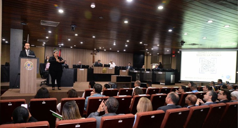 #PraTodosVerem: Na fotografia aparece um homem se dirigindo ao público. Do seu lado esquerdo, um...