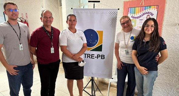 Foto 2: #PraTodosVerem: Na fotografia aparece um grupo de cinco pessoas em pé, posando ao lado d...