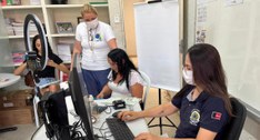 #PraTodosVerem: Na fotografia aparece uma mulher operando um computador em primeiro plano. Ao ce...