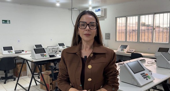 nvi_preparacao_urnas_cabedelo_3 Foto 3: #PraTodosVerem: Na fotografia aparece uma mulher, em pé, em uma sala, posando. Em segund...