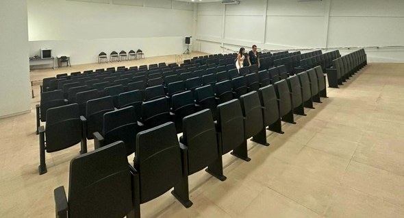 #PraTodosVerem: Na fotografia aparece um auditório vazio, com longas fileiras de poltronas preta...