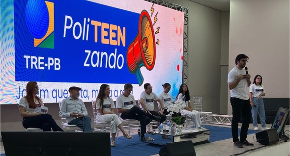 #PraTodosVerem: Na fotografia aparece um painel de debate com cinco pessoas sentadas em cadeiras...