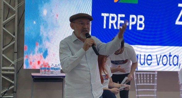Foto 3: #PraTodosVerem: Na fotografia aparece um homem, em pé em um palco, gesticulando com o br...