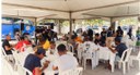 #PraTodosVerem: Na fotografia aparecem pessoas fazendo refeição em mesas de plástico embaixo de ...