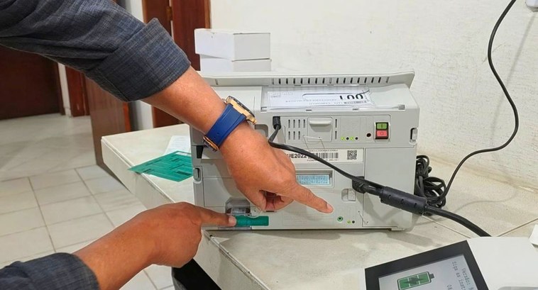 #Pratodosverem: na foto, aparece a parte traseira de uma urna eletrônica e mãos indicando o proc...