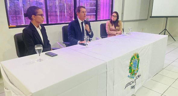 #PraTodosVerem: Na fotografia aparecem duas mulheres e um homem, sentados a mesa de honra de um ...