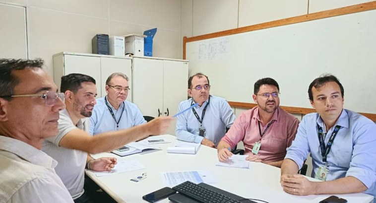 #PraTodosVerem: Na fotografia aparece uma sala de reunião com uma mesa branca retangular. Seis h...