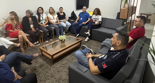 roda_de_conversa_cg_2 #PraTodosVerem: Na fotografia aparece um grupo de pessoas sentadas em sofás e cadeiras, formando...