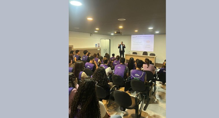 #PraTodosVerem: Fotografia de um auditório onde jovens vestindo camisetas roxas assistem a uma p...