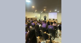 #PraTodosVerem: Fotografia de um auditório onde jovens vestindo camisetas roxas assistem a uma p...