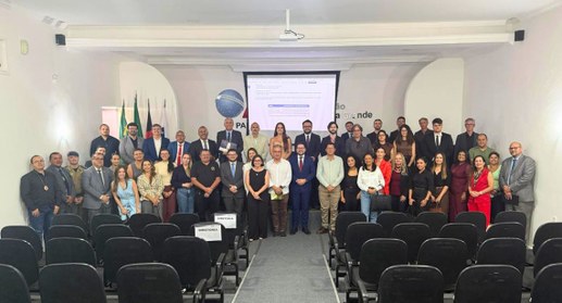 #PraTodosVerem: Na fotografia aparece um grupo de pessoas posando para fotos em pé num auditório 
