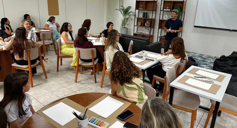 #PraTodosVerem: Na fotografia aparecem pessoas reunidas em uma sala para uma oficina de pintura.