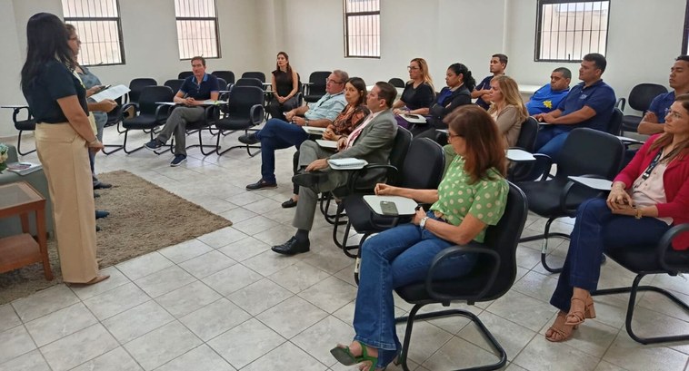 Servidores do TRE-PB participam de reunião de orientação na APAE-JP sobre o Projeto Cuidar #PraTodosVerem: Na fotografia aparecem pessoas sentadas em cadeiras, enquanto duas mulheres, em ...