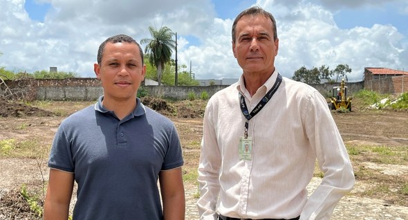 Sustentabilidade e economia: usina fotovoltaica entra em fase física_1 #PraTodosVerem: Na fotografia aparecem dois homens posicionados lado a lado em um terreno aberto...