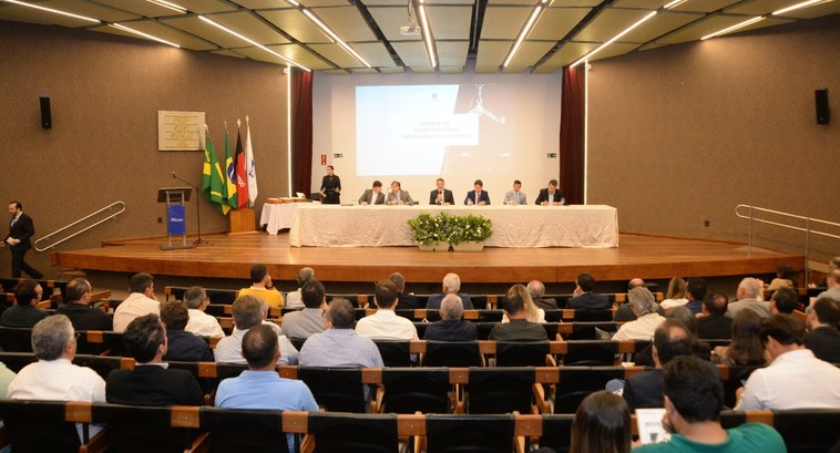 TRE-PB apresenta proposta de valorização dos servidores requisitados #PraTodosVerem: Na fotografia aparece um auditório, com pessoas sentadas em poltronas.