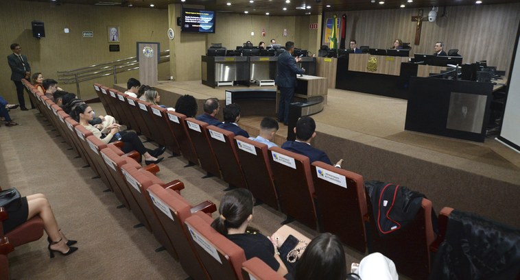 TRE-PB audiência pública realizada Painel retangular, mostrando de cima pessoas numa sala de sessões de julgamento, participando de...