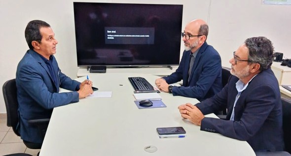 TRE-PB avança com o projeto “Zona Eleitoral Segura” #PraTodosVerem: Na fotografia aparece uma sala de reunião com uma mesa branca retangular. Três h...