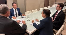 #PraTodosVerem: Quatro homens sentados à mesa de vidro, conversando e analisando documentos, com...