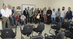 Servidoras e servidores posando para fotografia numa sala de aula, três pessoas estão ajoelhadas...