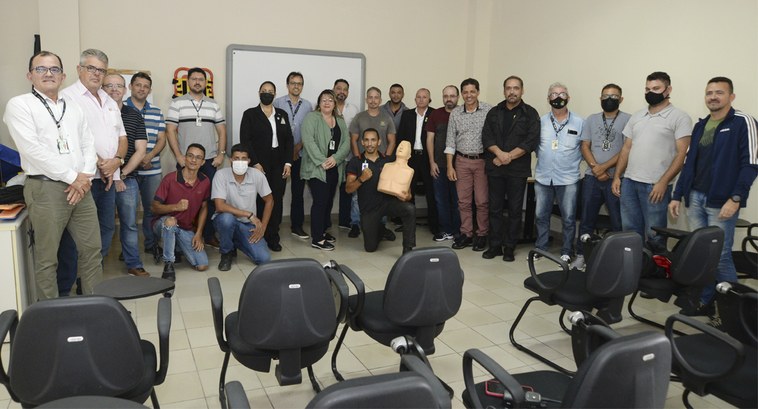 Servidoras e servidores posando para fotografia numa sala de aula, três pessoas estão ajoelhadas...