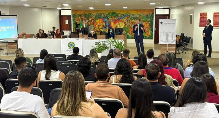 TRE-PB dá posse a 22 estagiários que vão trabalhar em zonas eleitorais PraTodosVerem: Auditório com plateia cheia, onde um homem de terno fala em pé, enquanto autorida...